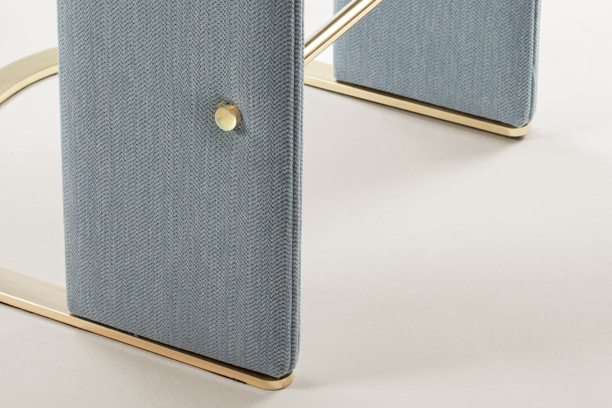 Odisseia Counter Stool close-up of the brass footrest and stud on blue fabric