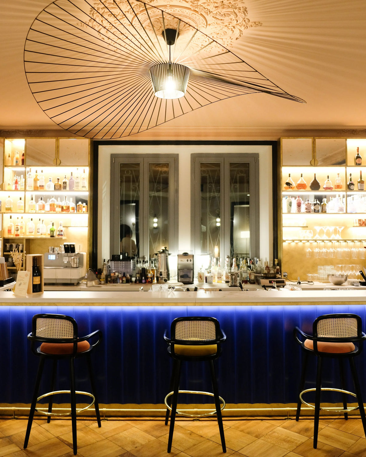 Luc bar chairs along a blue-lit hotel bar