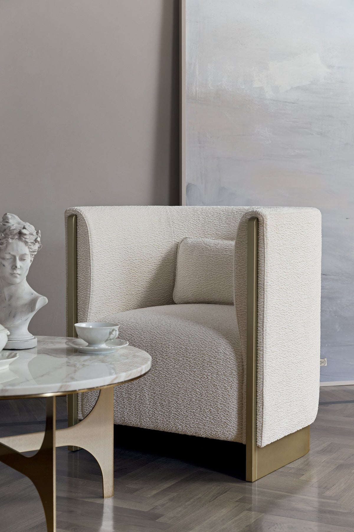 Adeline Armchair in ivory with lumbar cushion beside a marble side table
