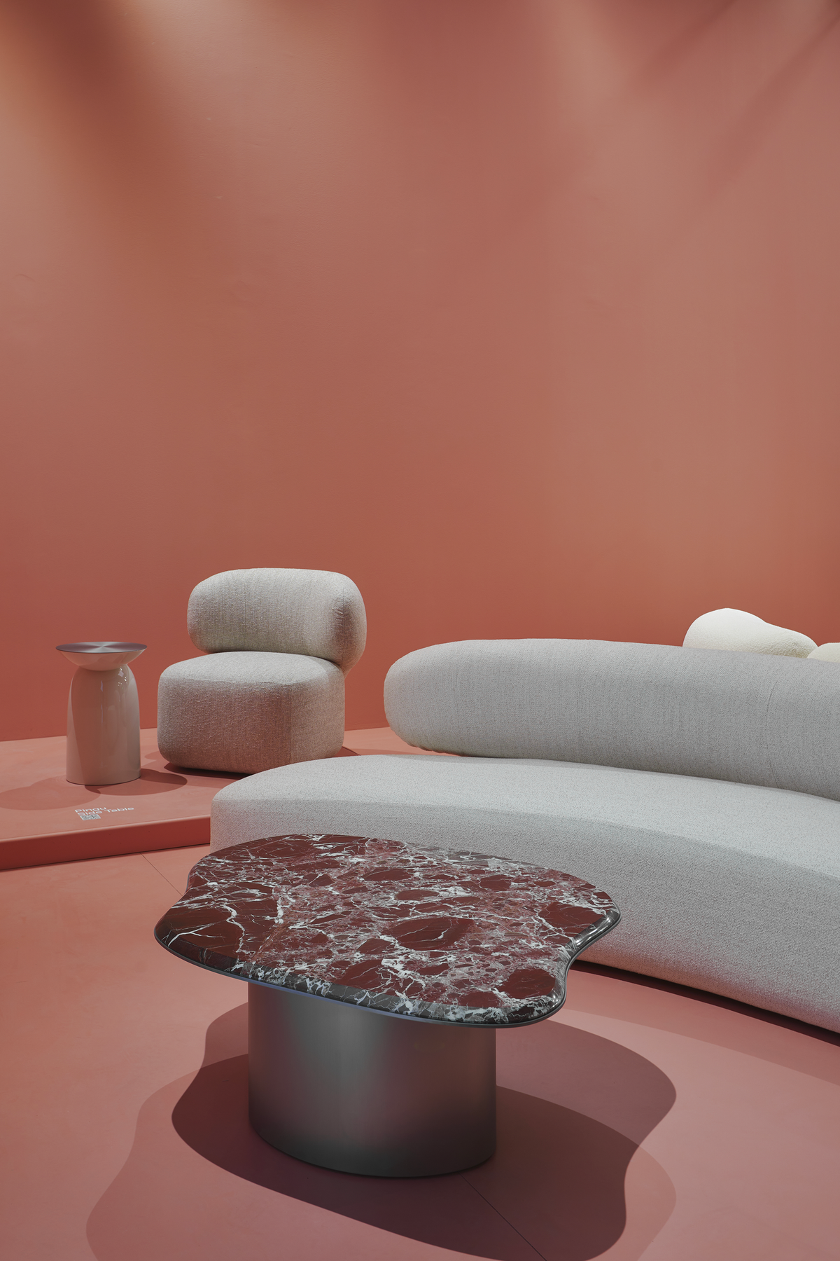 Asawa Lounge Chair in a coral-pink room with a curved sofa and red marble coffee table