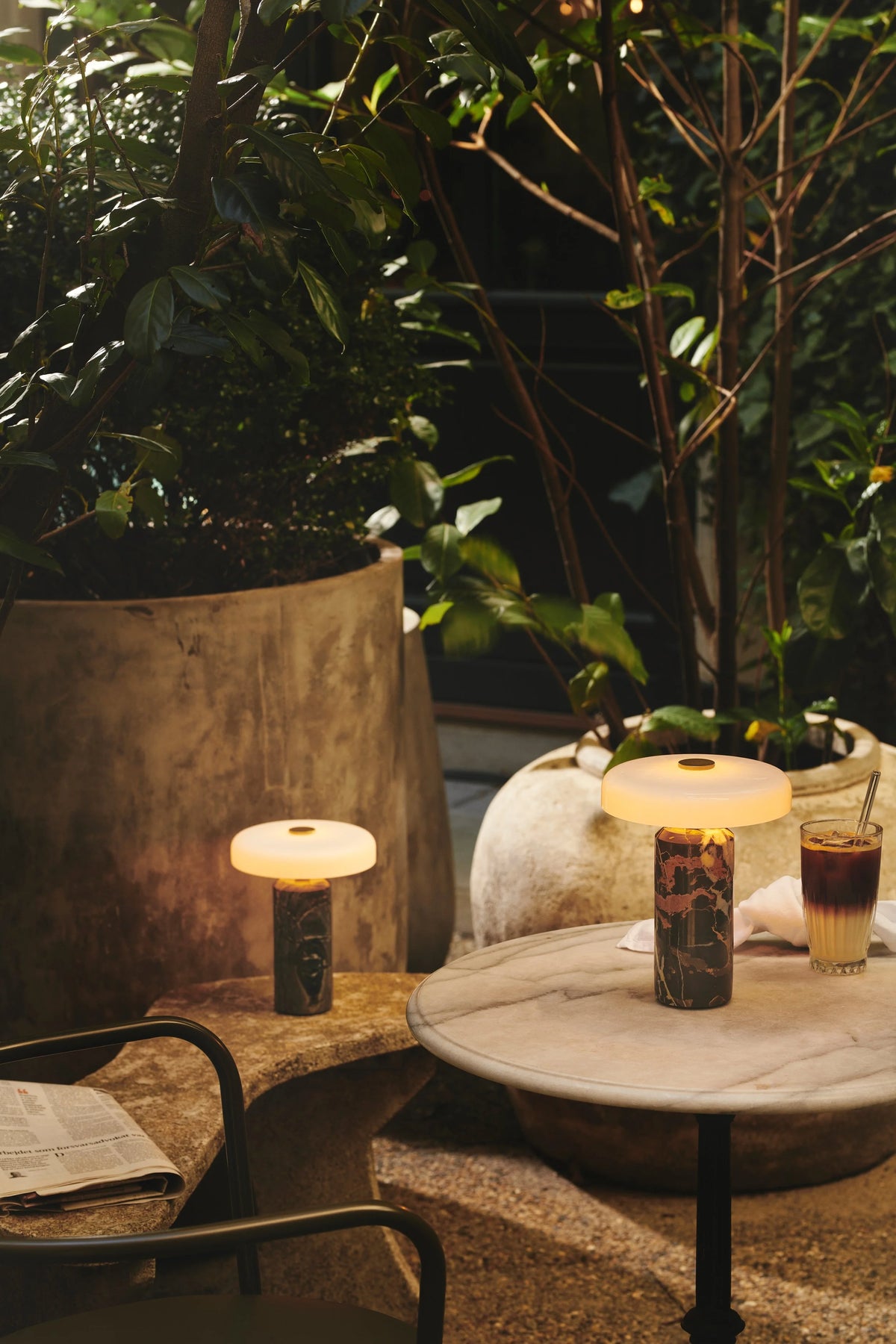 Trip Table Lamp – Dark Clay | Opal lit on a garden table at dusk
