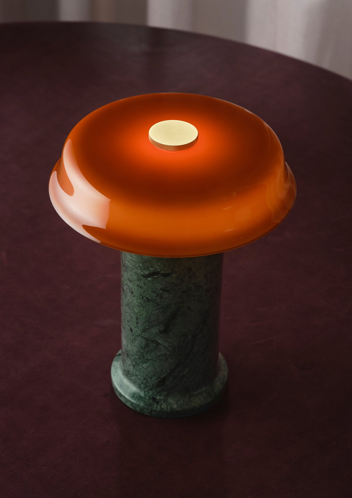 Trip 2 Table Lamp in Moss / Amber lit on a deep red tabletop