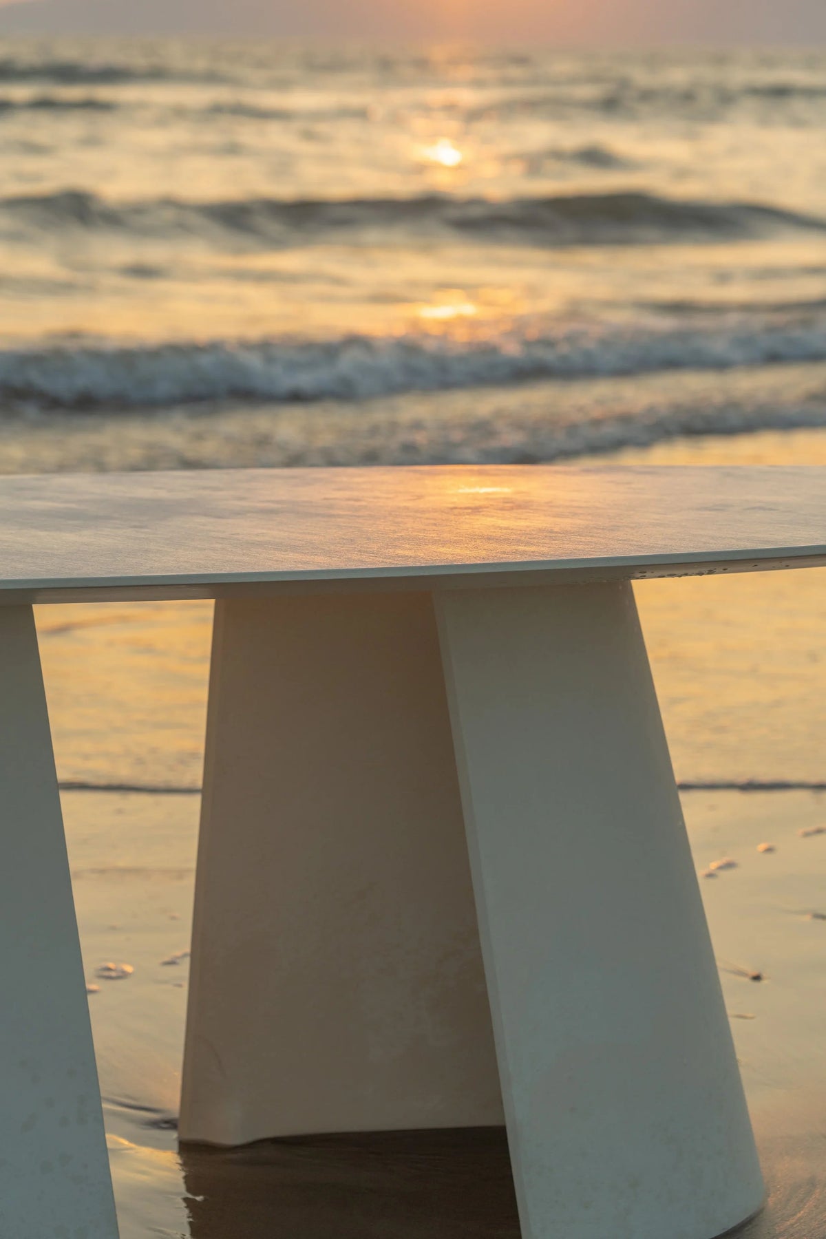 Tumuli Oval Dining Table close-up of the base on wet sand at sunset