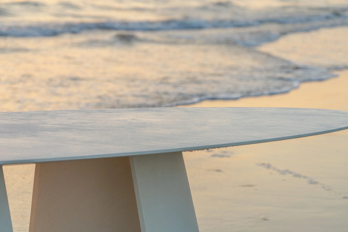 Tumuli Oval Dining Table top edge and base against waves on the beach