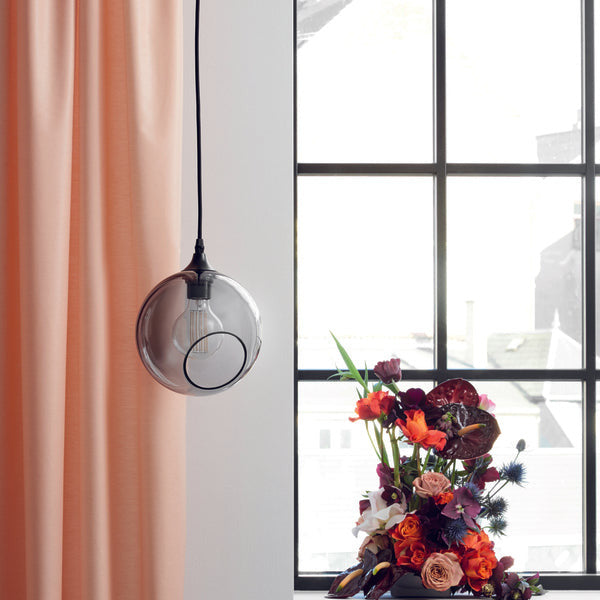 Ballroom Smoke Pendant Light by a window with sheer pink curtains and flowers