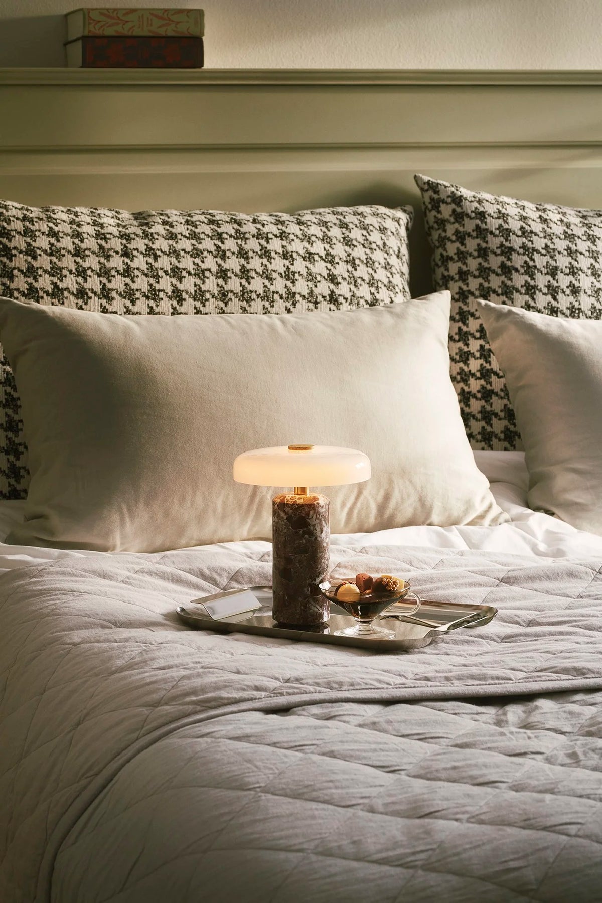 Trip Table Lamp – Burgundy | Opal glowing on a bedside tray, close view of the bed setting