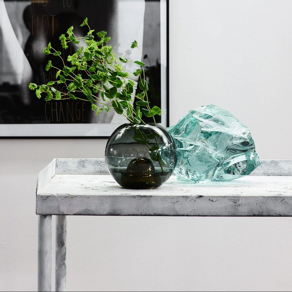 Vase Flower Bullet - Smoke with greenery beside an aqua glass piece on marble