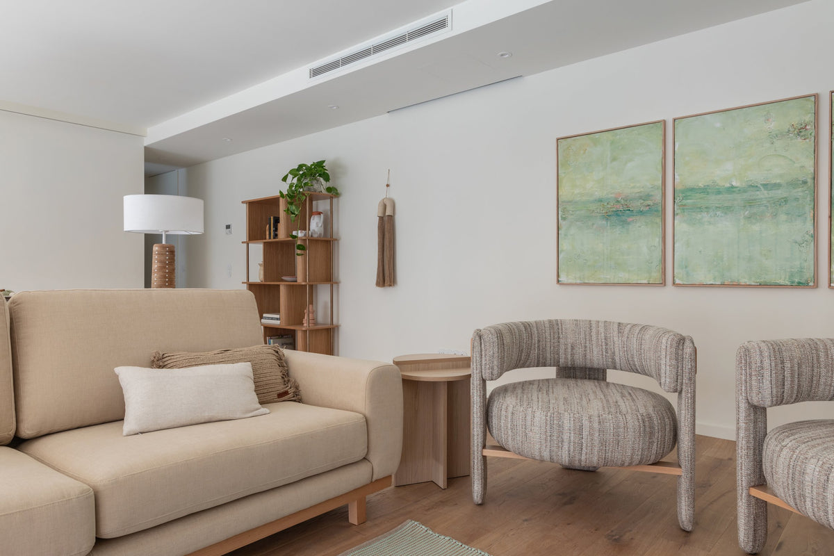 Choux Armchair in grey weave beside a beige sofa in a bright living room