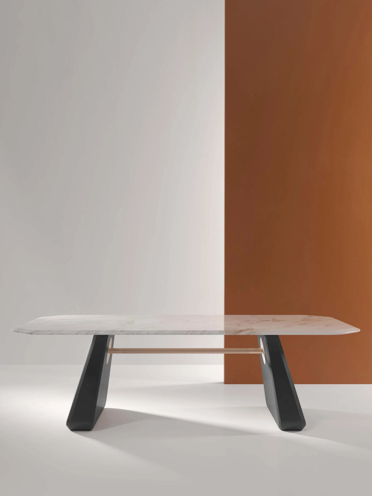 Inge Dining Table with white marble top and dark legs against a rust wall