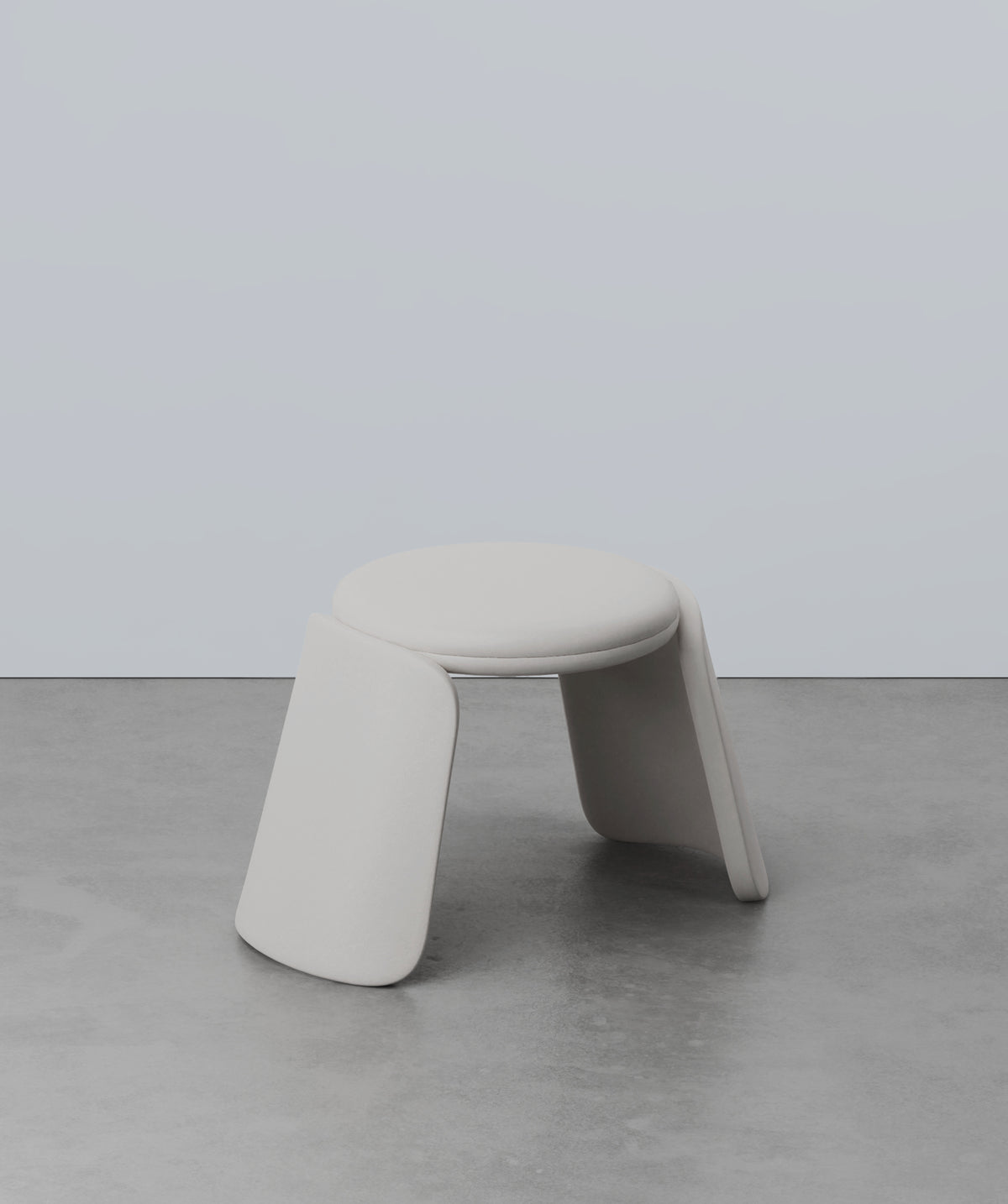 Inge Pouf in light grey on a concrete floor, three-quarter view