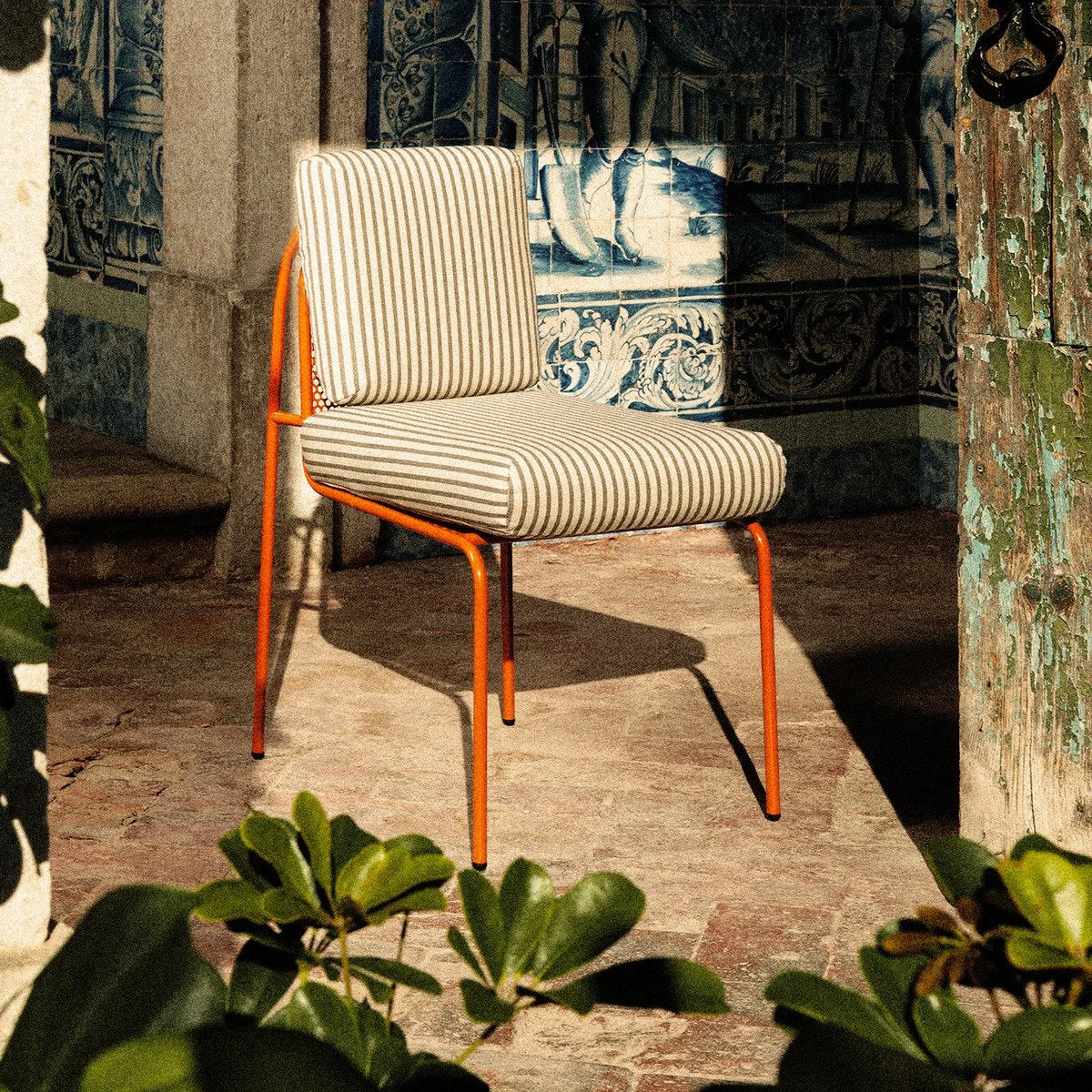 Riviera Chair in Awning Stripe with terracotta frame by blue tile walls