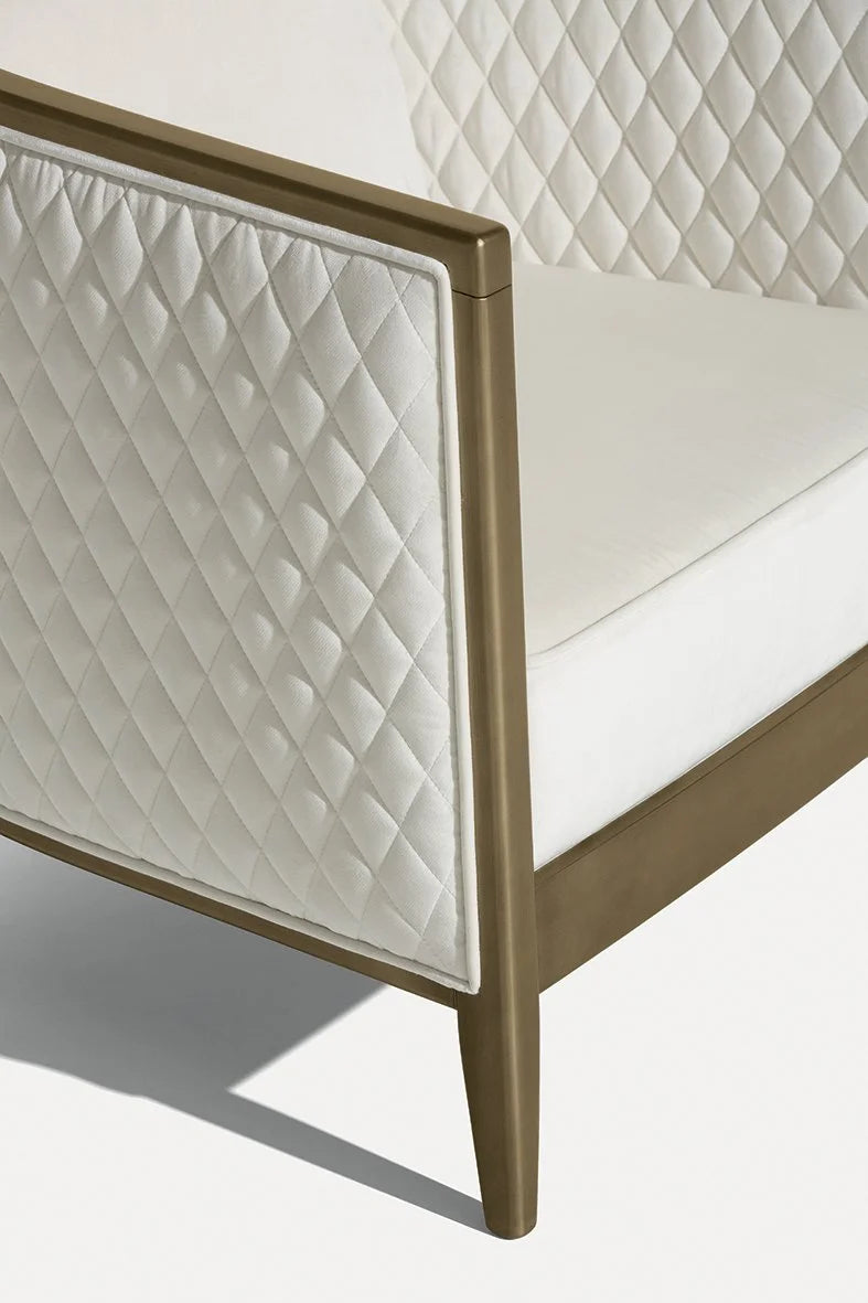 Saten Armchair, close-up of the white quilted side panel and bronze-tone leg