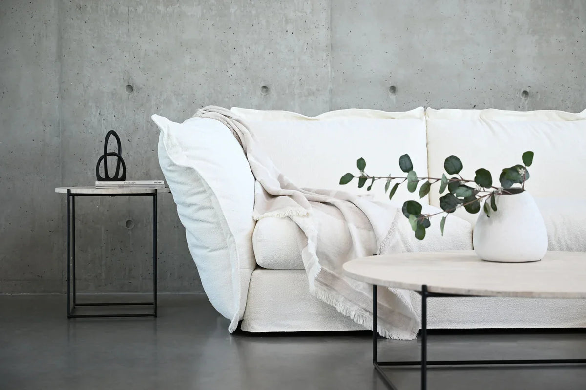Willow Sectional Sofa in white with a throw and side table by a concrete wall