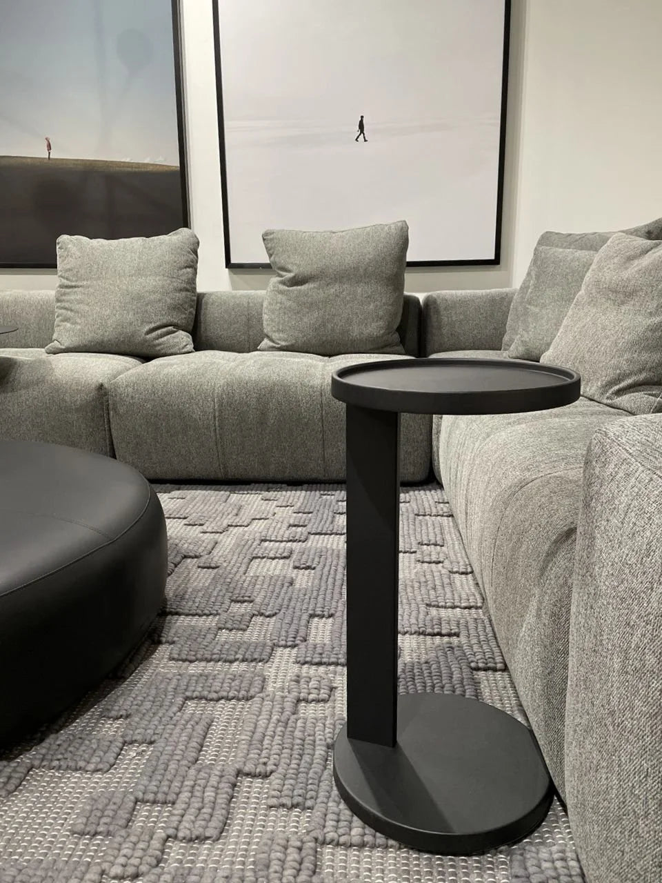 Rookie End Table in Matte Black tucked against a grey sectional