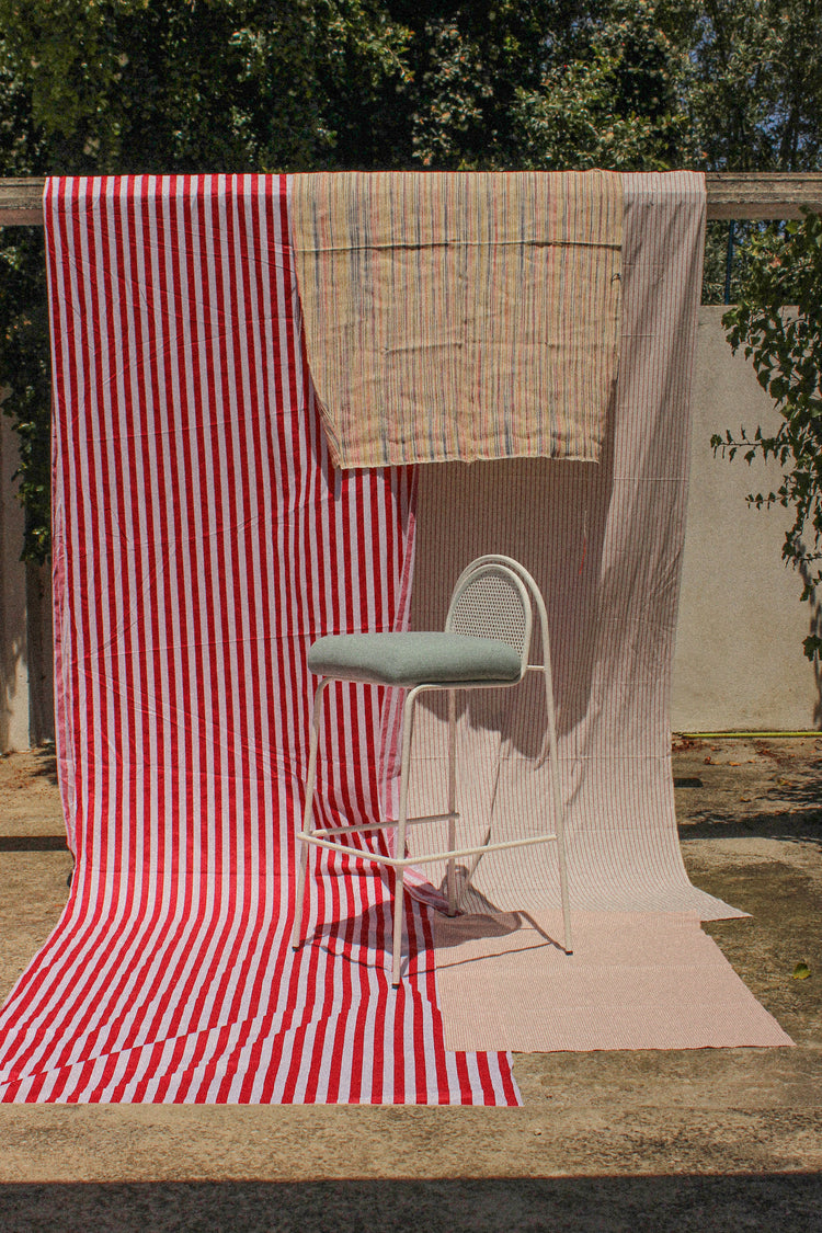Riviera Bar Chair in white with sage seat on striped fabric outdoors