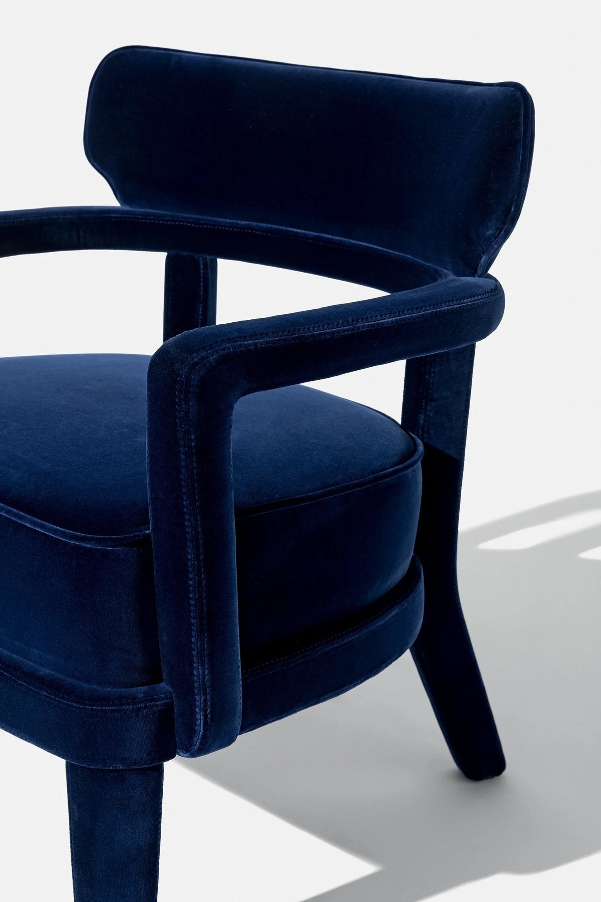 Zoe Armchair in navy velvet, close-up of the curved arm and seat