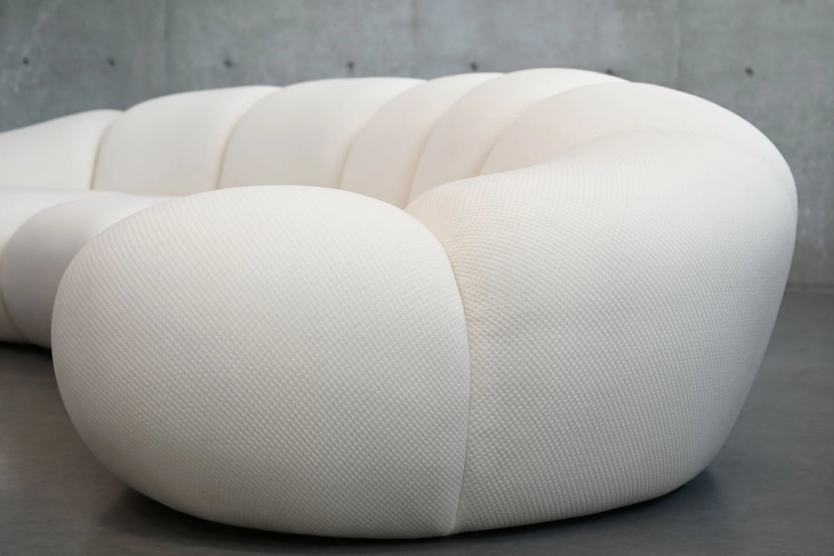 Cirro Sofa in Buttermilk, curved side view on a concrete floor
