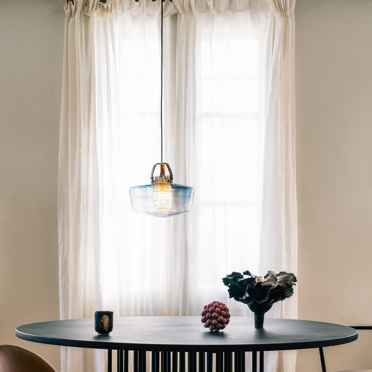 Addicted To Us pendant light in brass over a round dining table by Maison Burgos