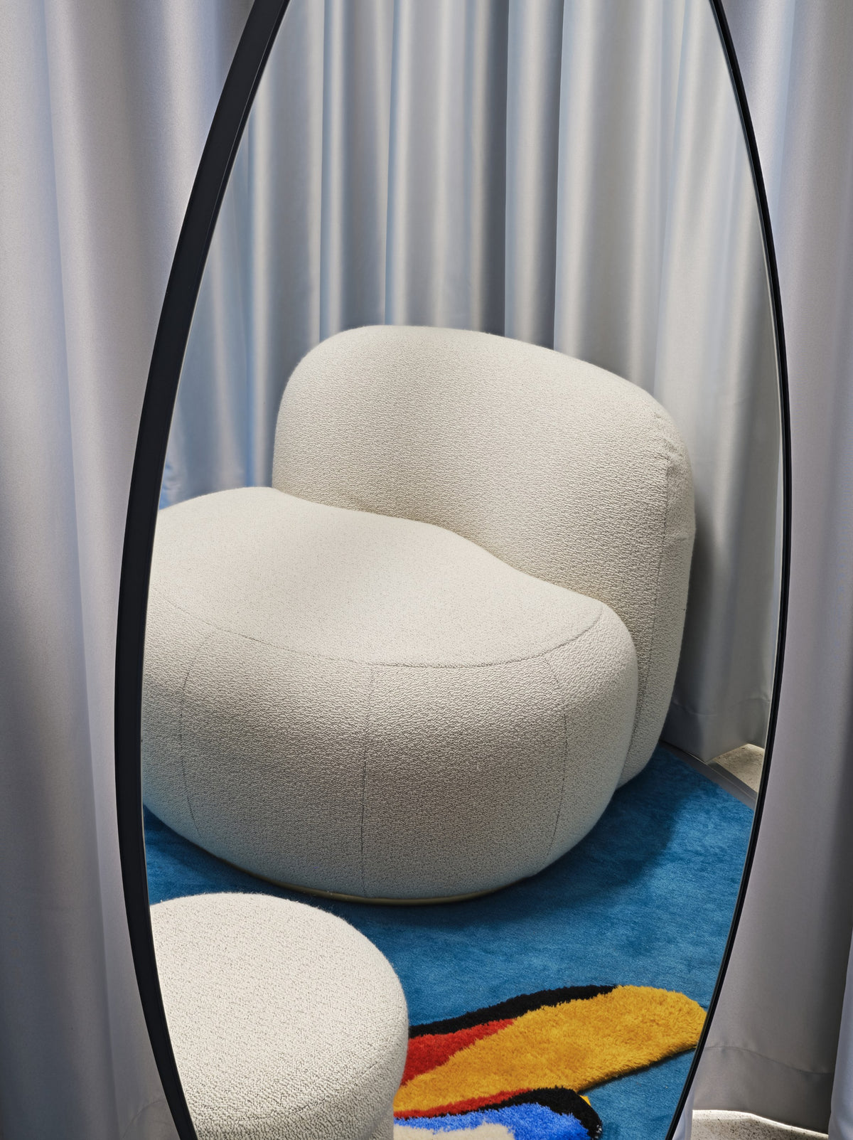 B-15 Z Lounge Chair in cream bouclé reflected in a tall mirror over a colourful rug