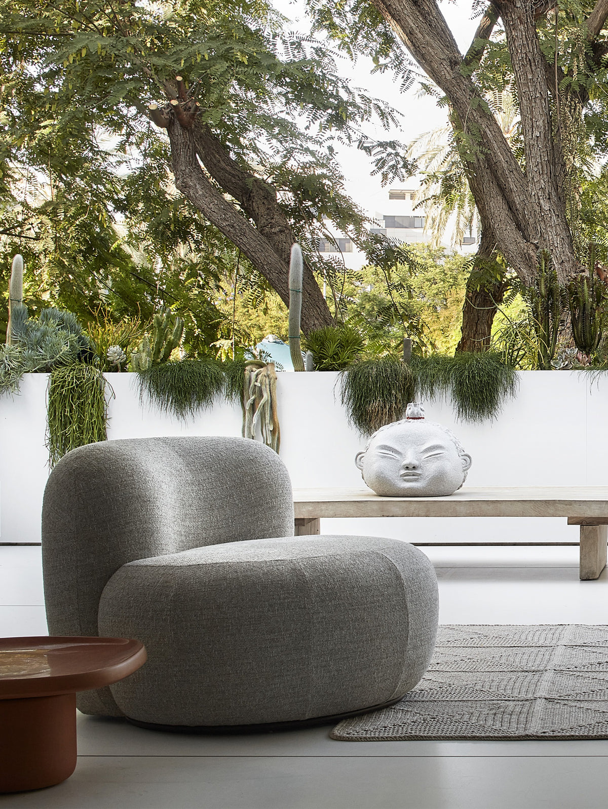 B-15 Z Lounge Chair in grey bouclé on an outdoor terrace under trees