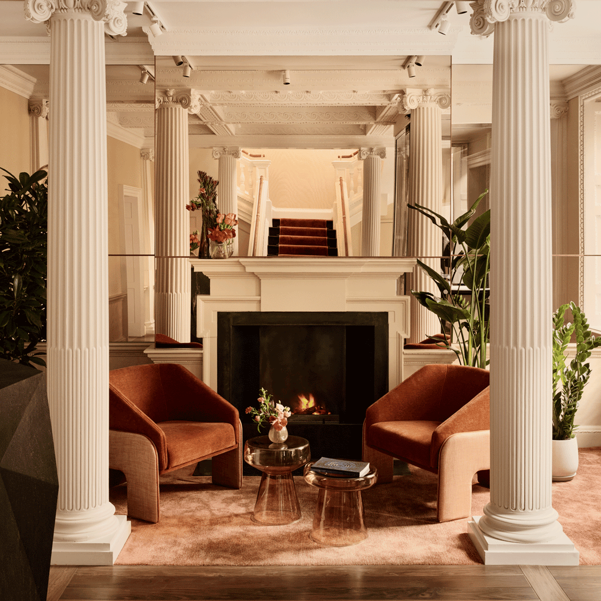 L’Unité Chairs in rust velvet by a fireplace between white columns