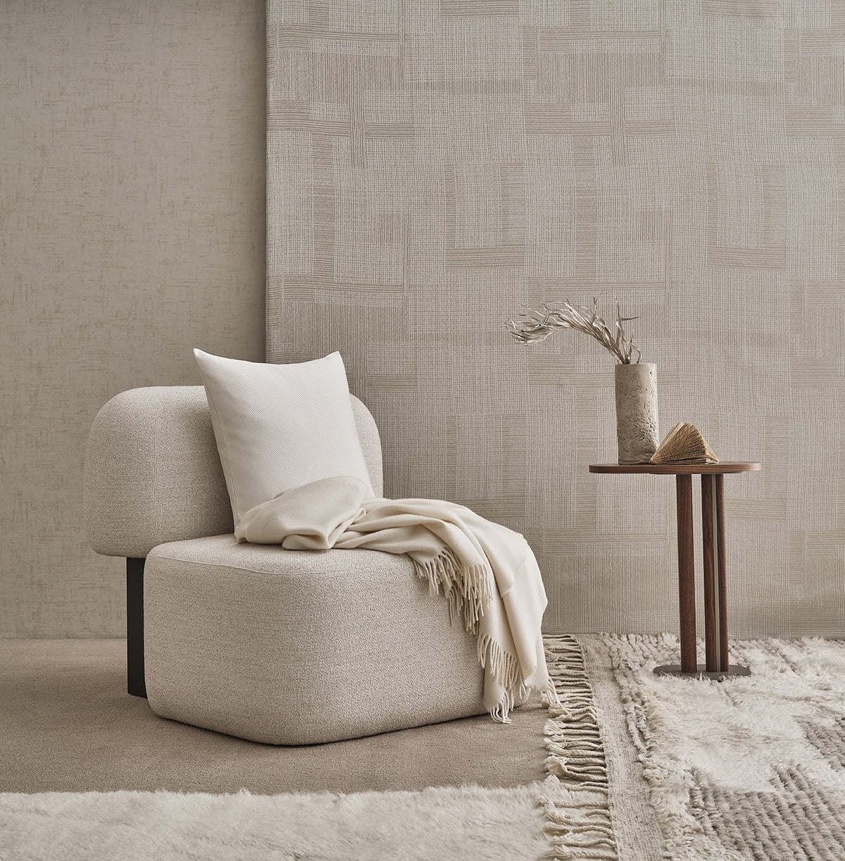 Yemeni Lounge Chair in cream boucle with a throw and cushion beside a slim side table