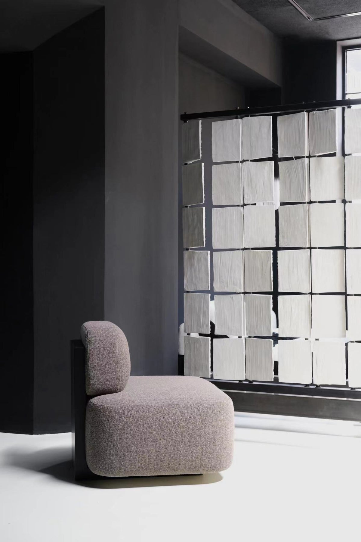 Yoshida Lounge Chair in taupe fabric in a dark room with a frosted glass wall