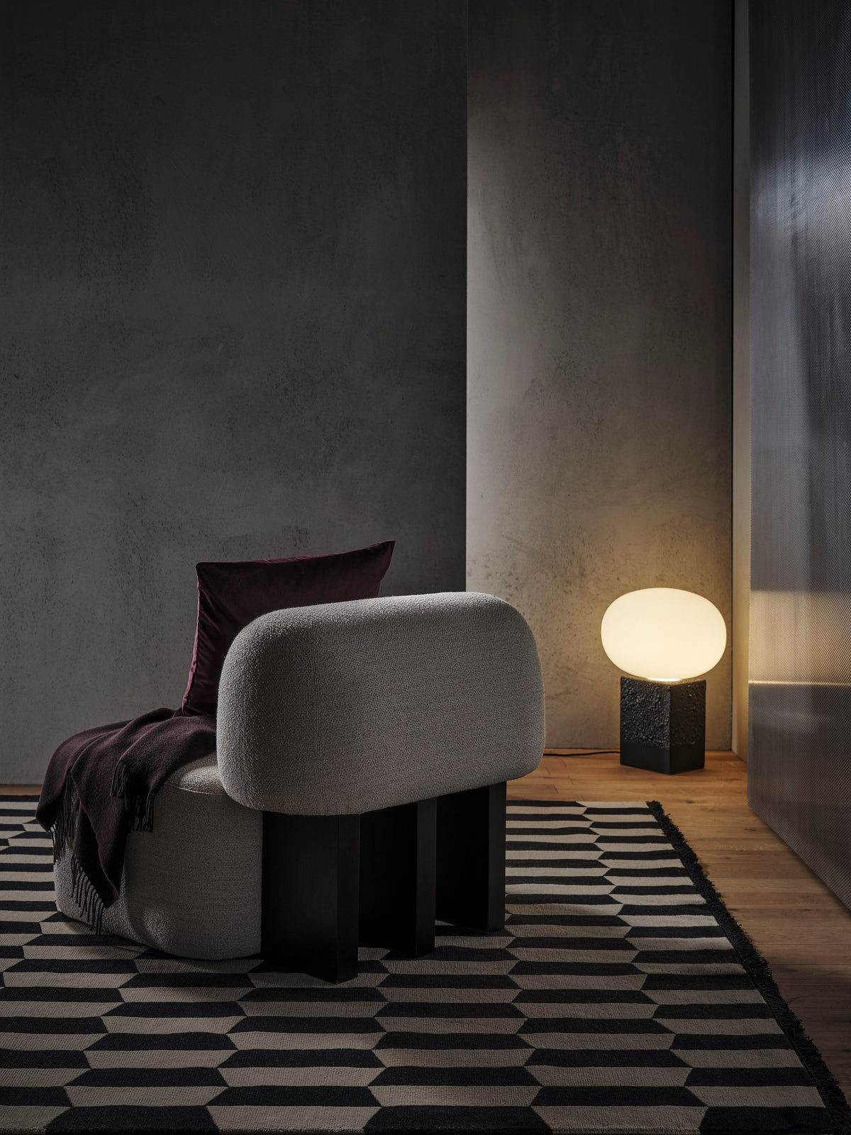 Yemeni Lounge Chair in grey upholstery with dark legs on a black and white geometric rug