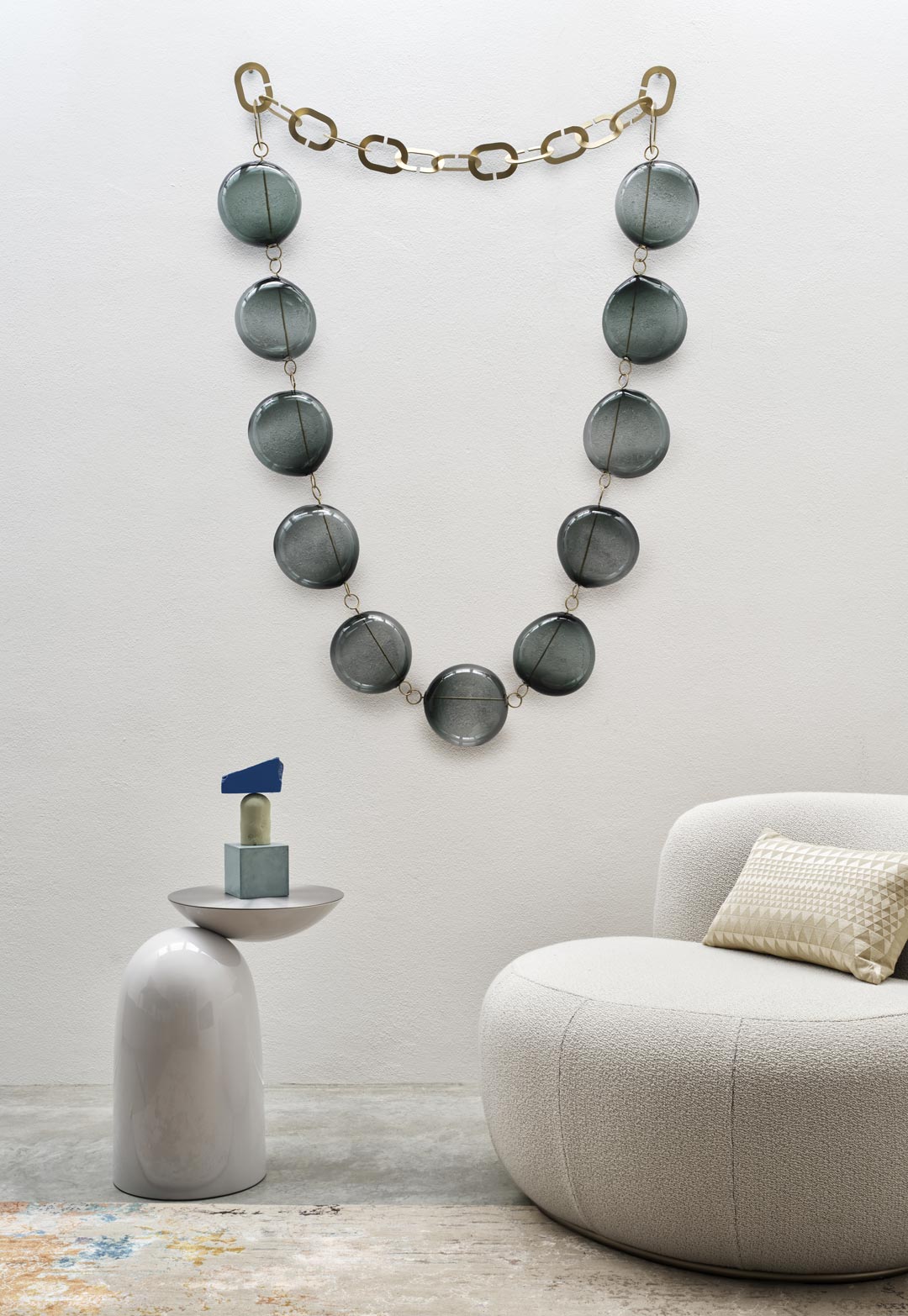 B-15 Z Lounge Chair in cream bouclé with cushion beside a side table under bead wall art
