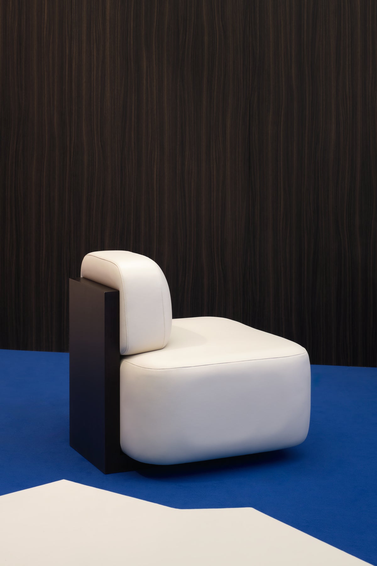 Yoshida Lounge Chair in ivory leather with dark wood side on a blue floor