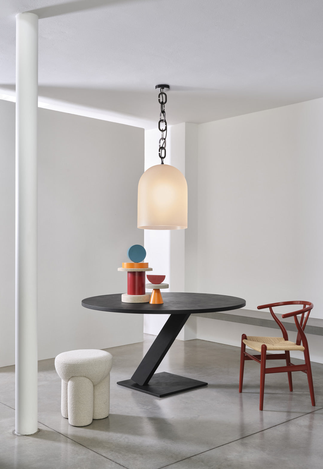Douglas Ottoman in cream bouclé beside a black dining table and red chair