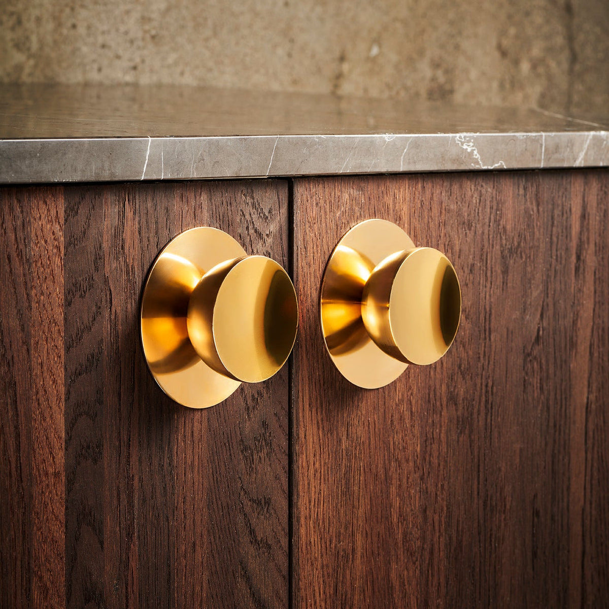 Get a Grip - Backplate Brass in brushed brass with knobs on a dark wood cabinet