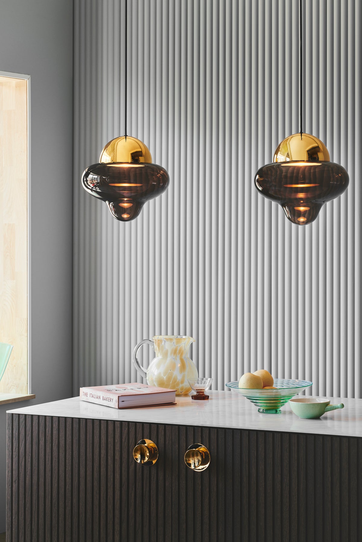 Get a Grip brass cabinet knobs on a kitchen island under pendant lights by Maison Burgos