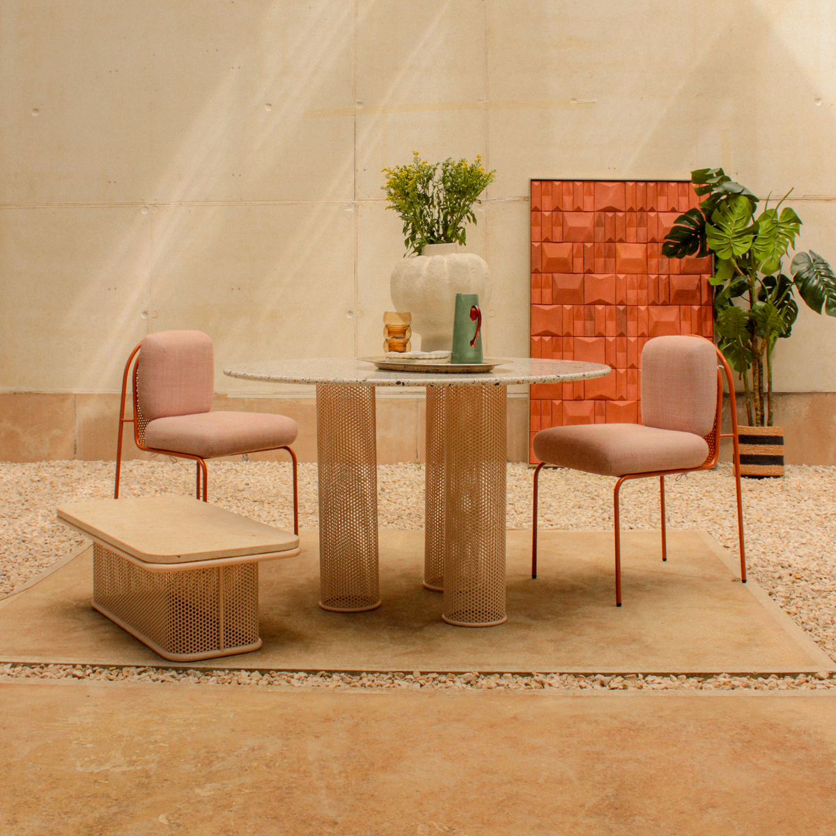 Terra Cota wall art behind blush chairs and a round table outdoors