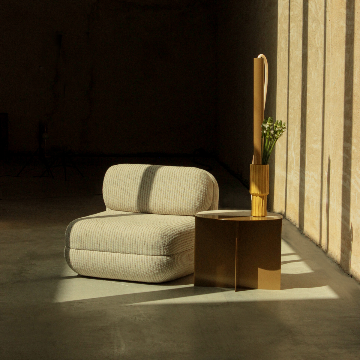 Mood Lounge Chair in beige weave next to a bronze side table in low light
