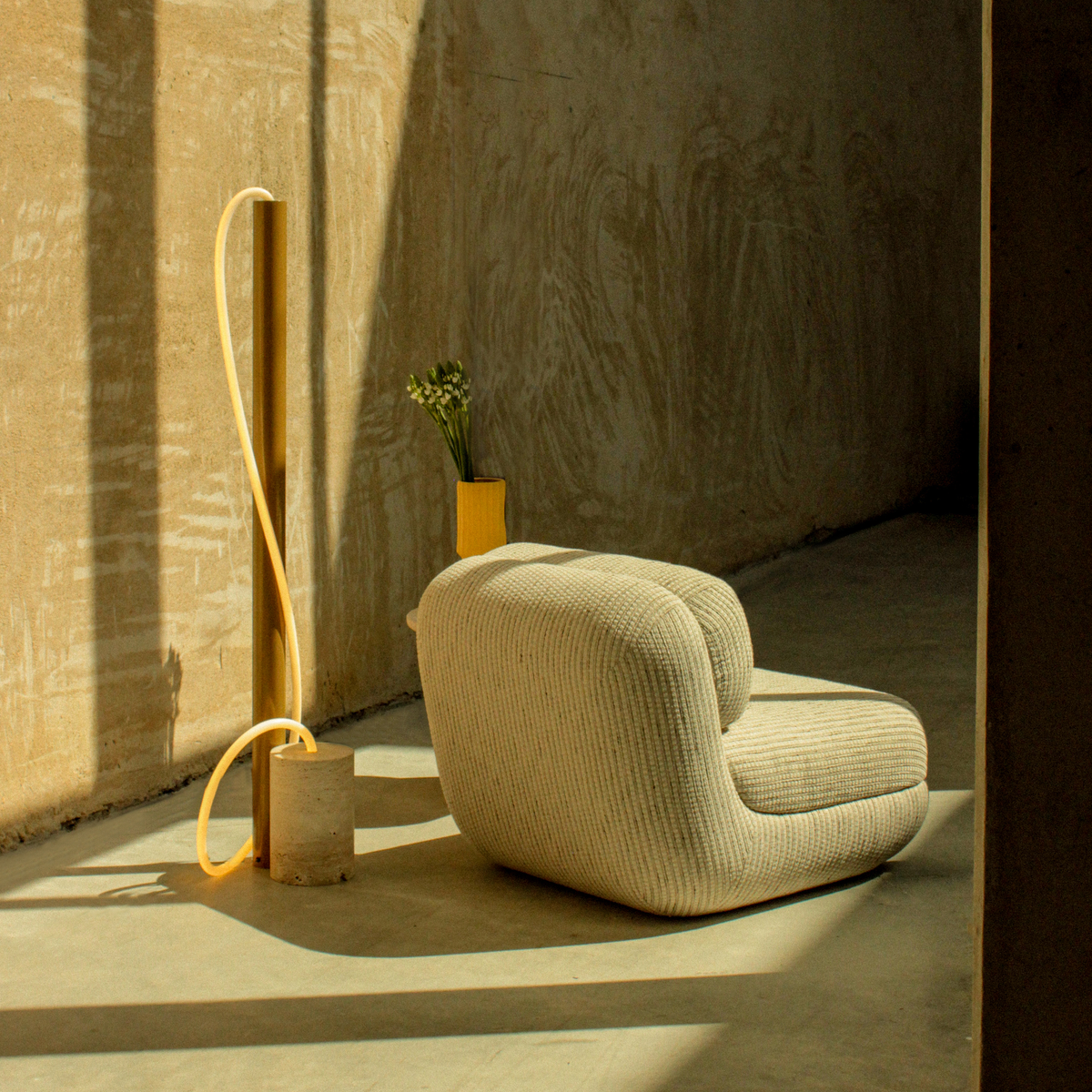 Mood Armchair in a sunlit concrete room beside a yellow tube lamp
