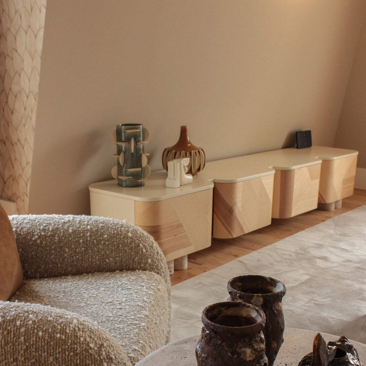 Kisho TV Stand in a warm living room beside a bouclé armchair and ceramic vases