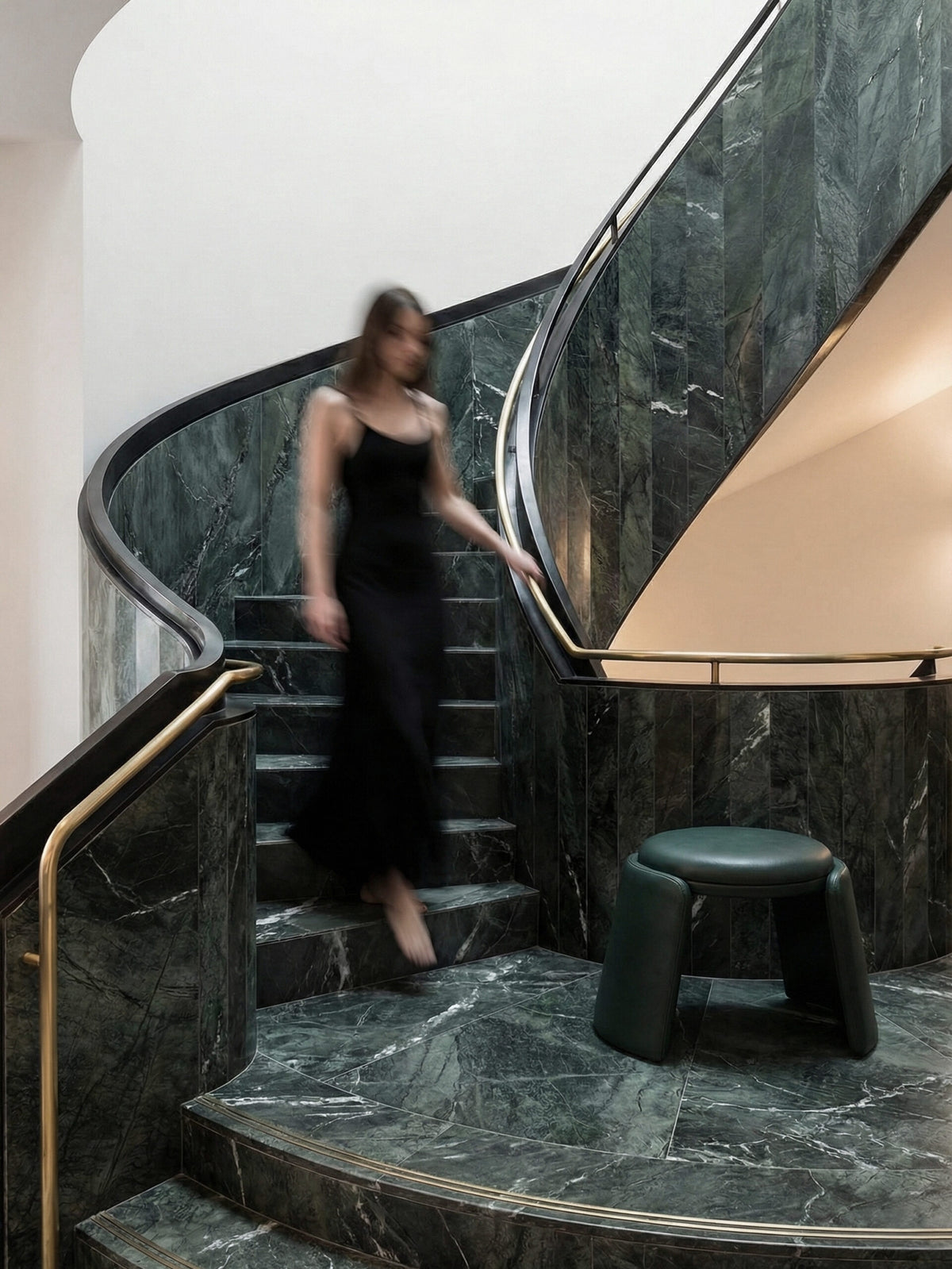 Inge Pouf in dark green leather at the foot of a marble staircase