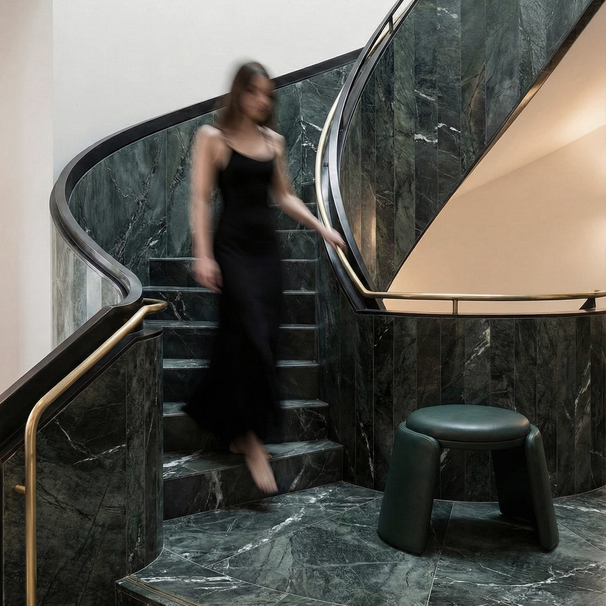 Inge Pouf in dark green leather on a marble staircase landing, wide view