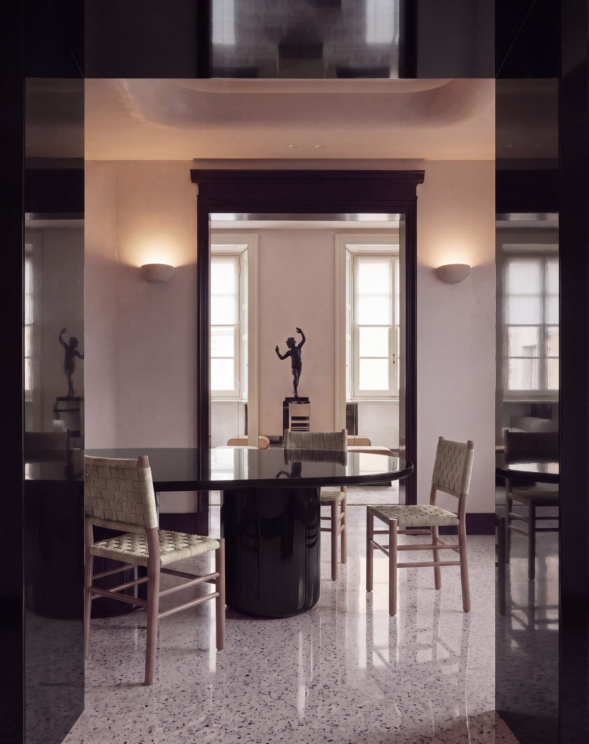 Laghi II Dining Table in black lacquer with rush chairs in a grand terrazzo-floored room