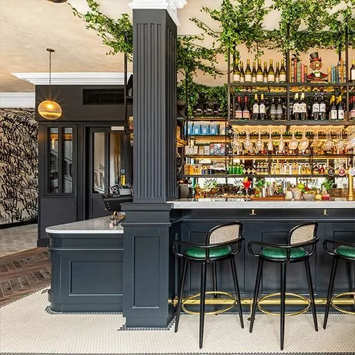 Luc bar chairs with green seats at a black hotel bar