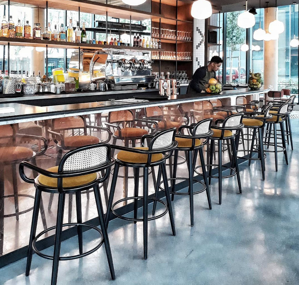 Luc bar chairs with mustard seats lining a cafe counter