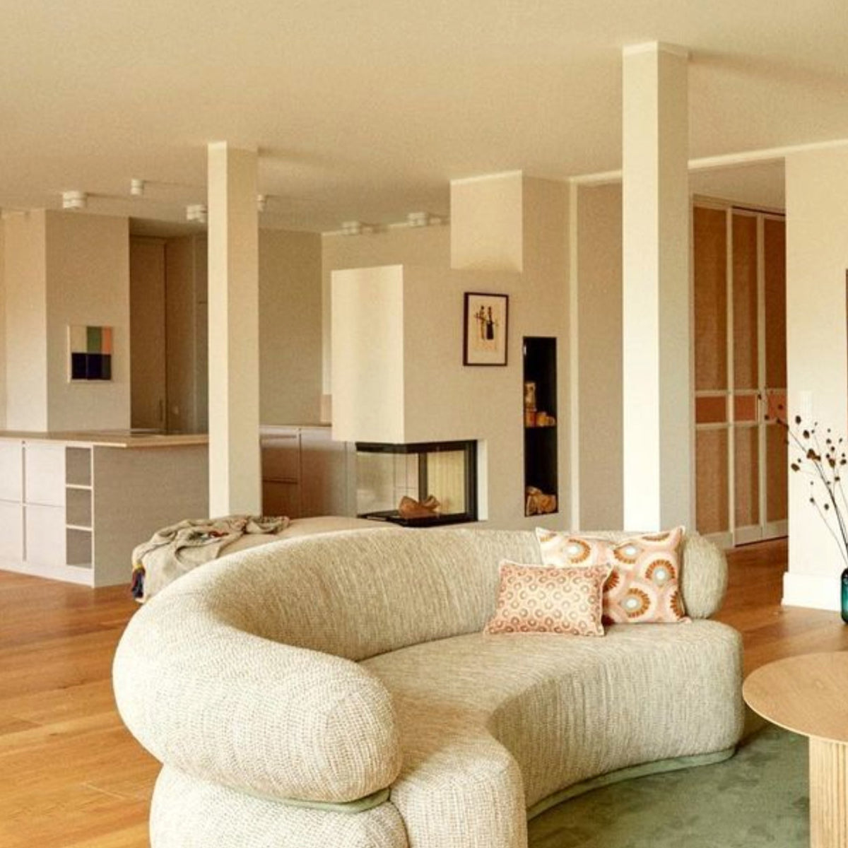 Malibu Curved Sofa in oatmeal bouclé with pink pillows in an open-plan home