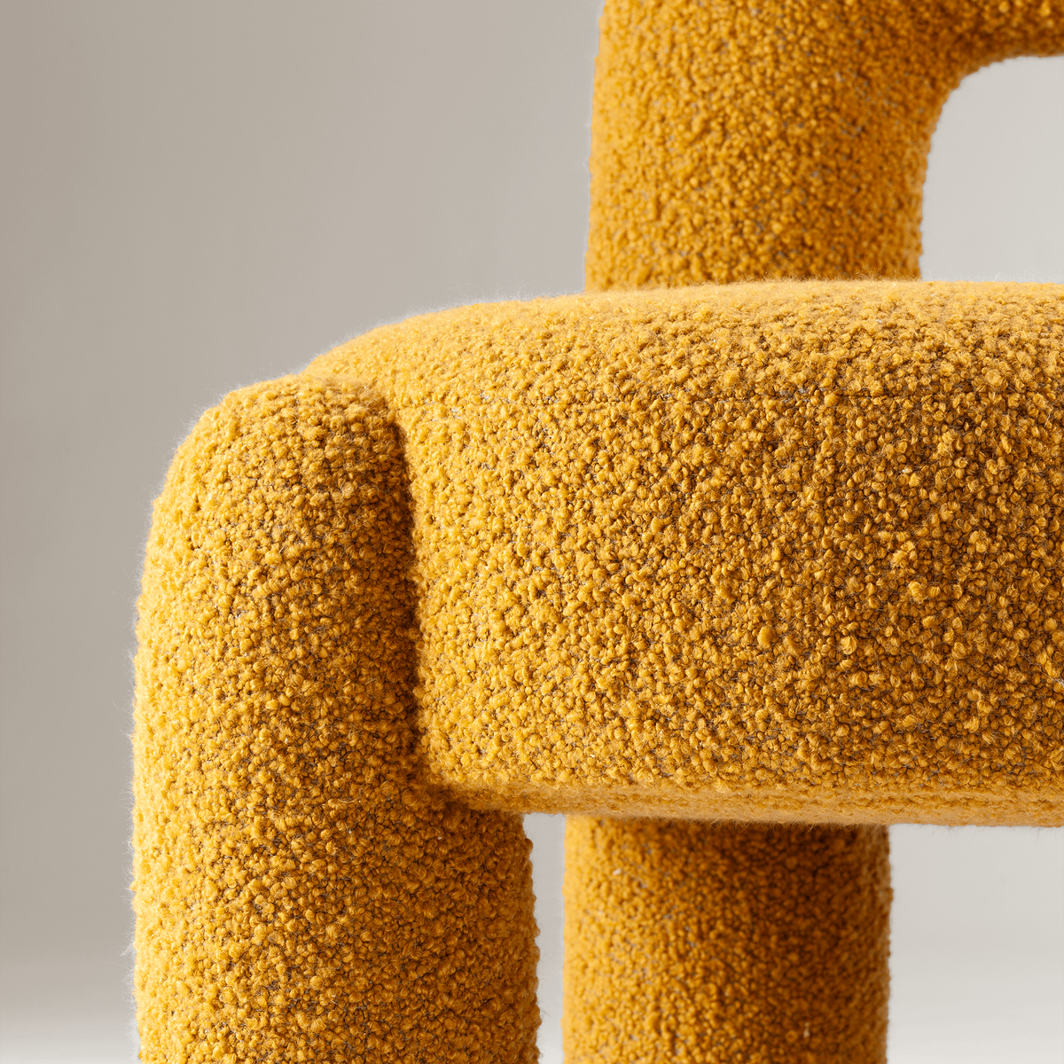 Marlon Armchair close-up of mustard bouclé seat and leg
