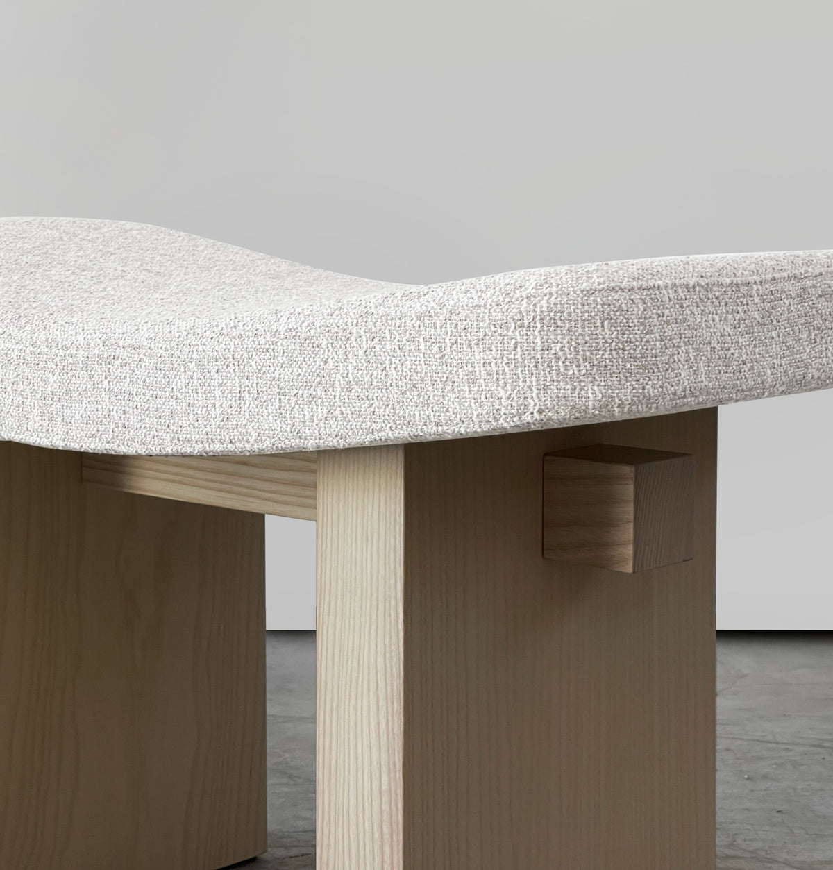Nara Ottoman close-up of the ivory bouclé seat and light wood joinery