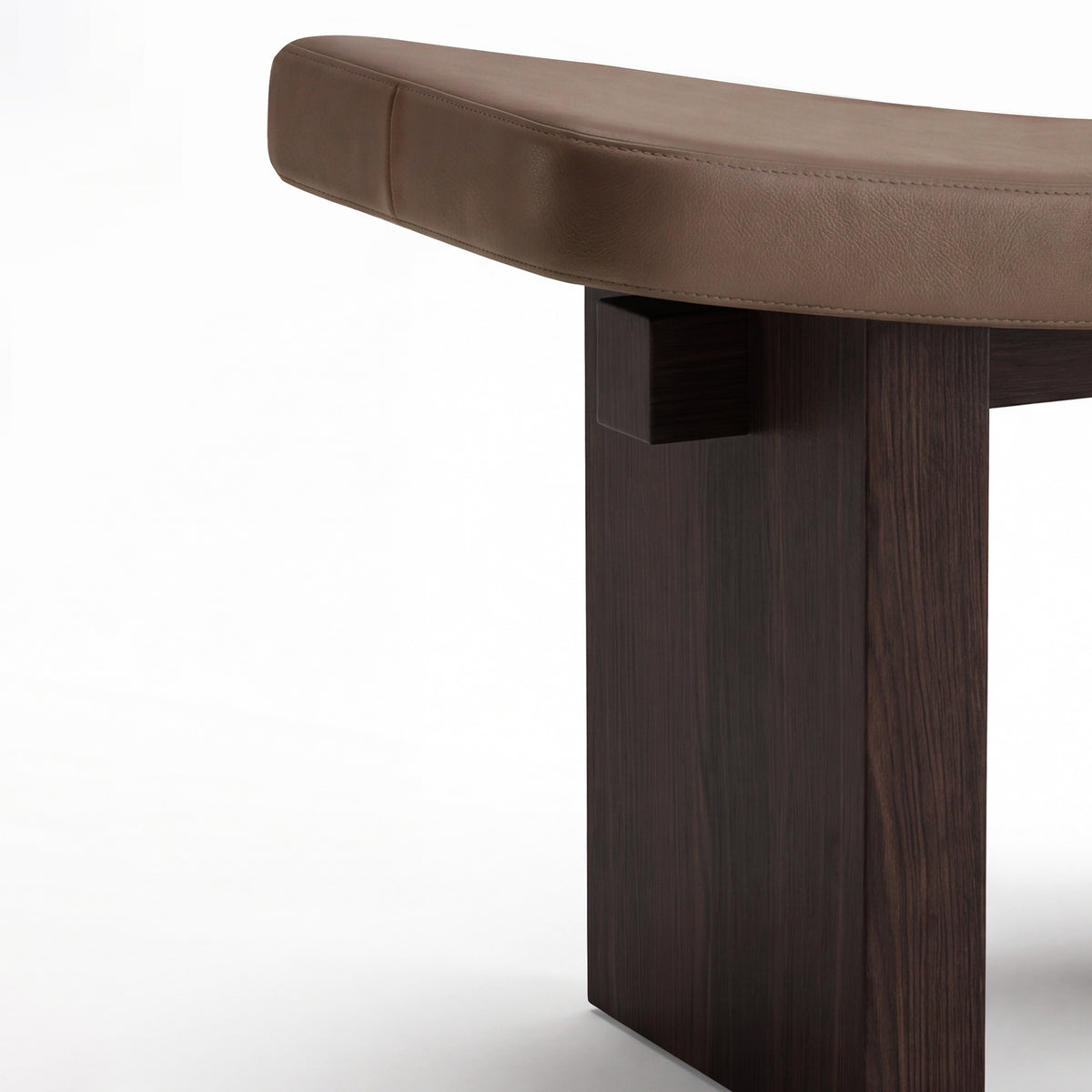 Nara Ottoman detail of the curved brown leather seat on a dark wood leg, right view