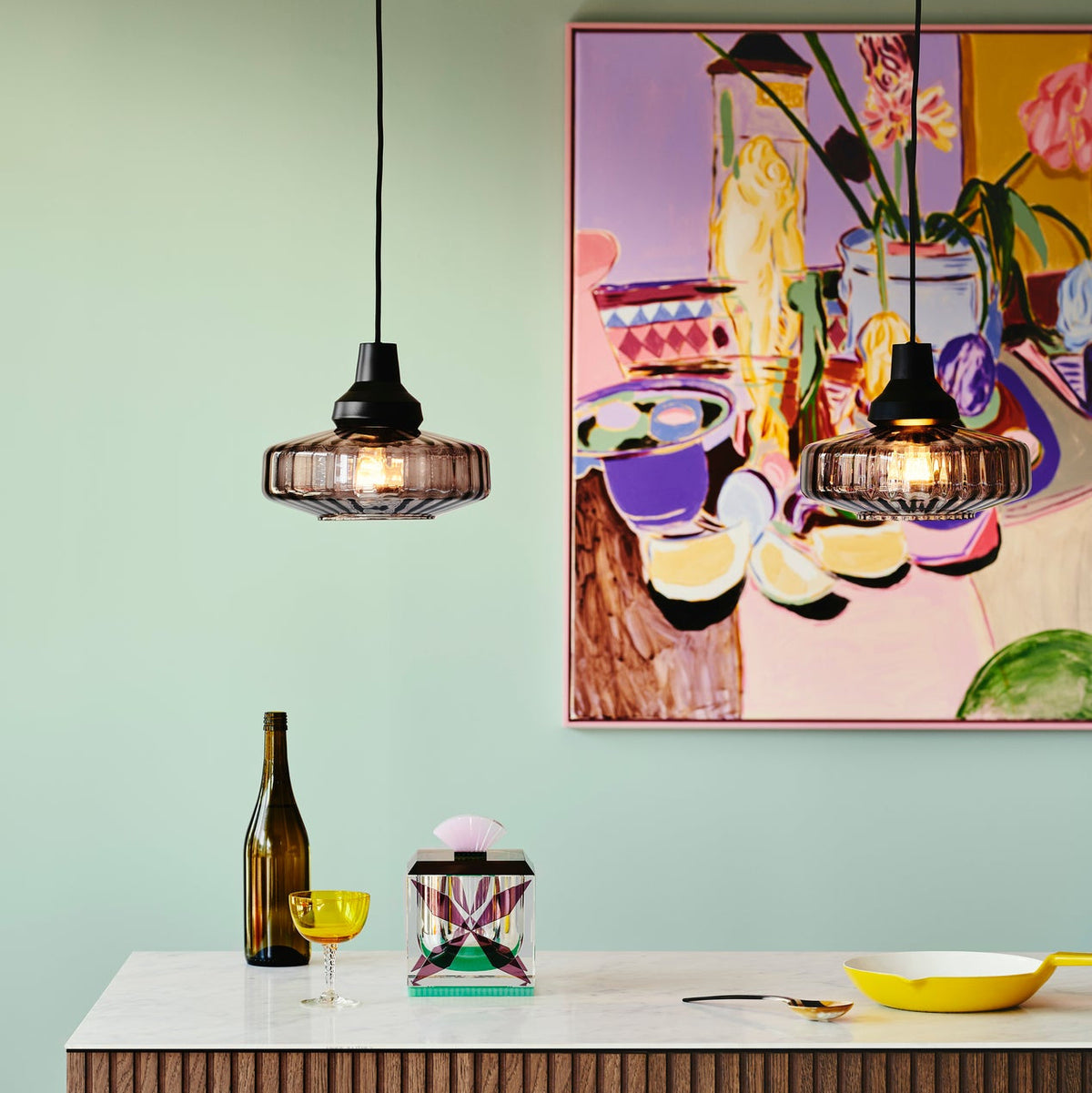 New Wave Optic Pendant Light Smoke pair hanging over a kitchen counter before a colourful painting
