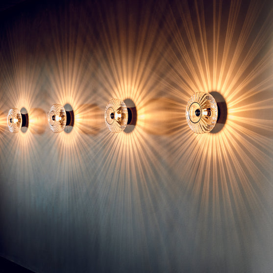 New Wave Optic Wall Sconce row of four lit sconces on a dark wall