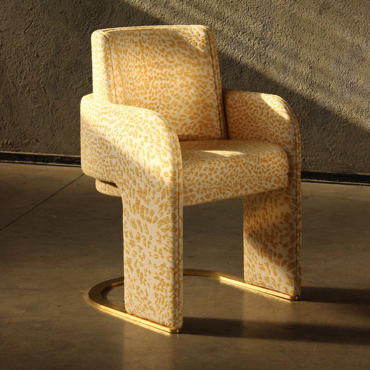 Odisseia Dining Chair in yellow leopard-print fabric in warm sunlight on a concrete floor