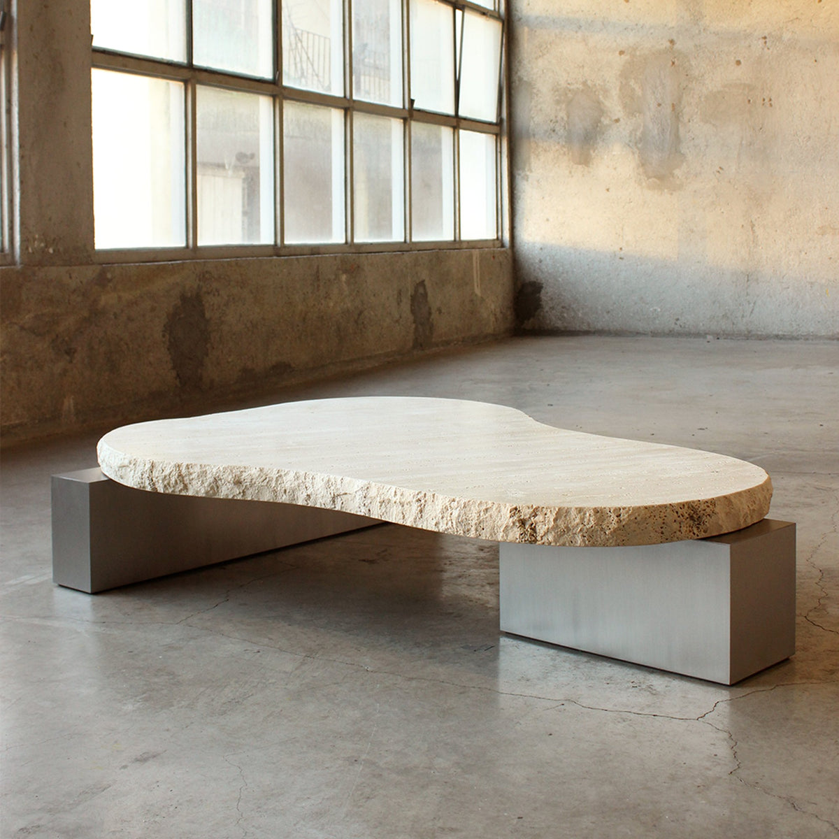 On The Rocks Coffee Table, travertine top, satin nickel base in a loft, by Maison Burgos